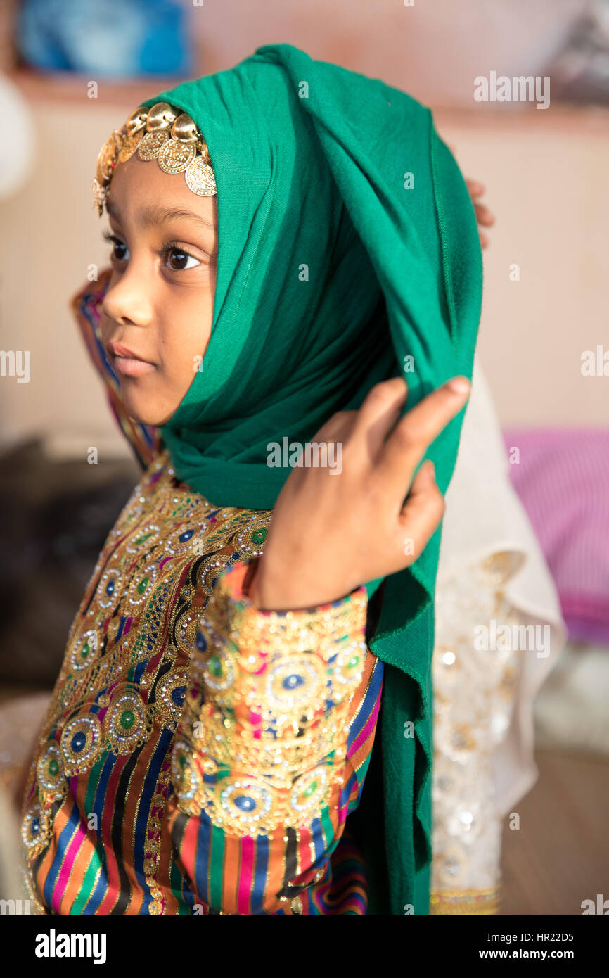 Young Omani girl in a traditional dress fixing her scarf. Stock Photo