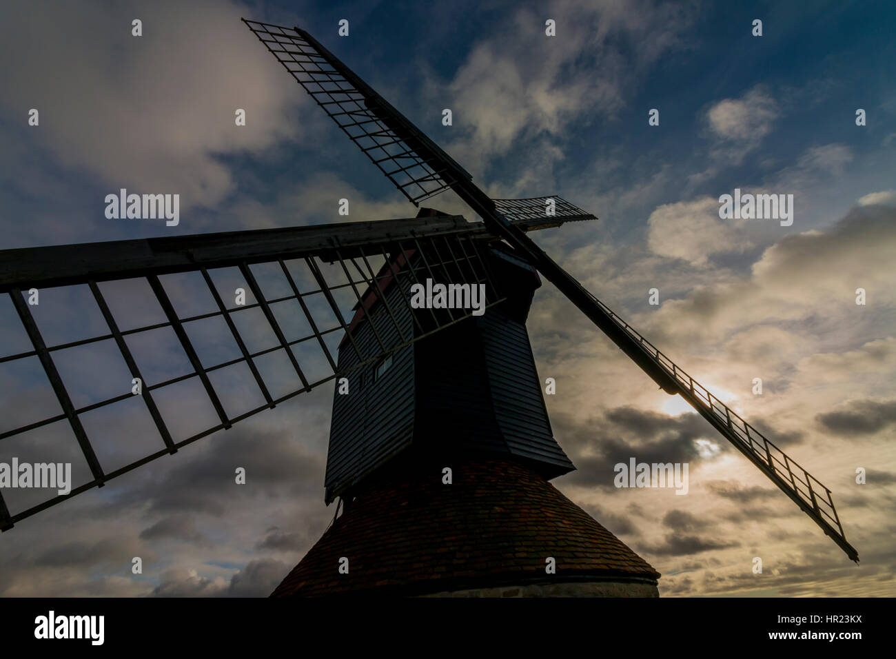 English windmill showing dynamic wide angle perspective of blades and early morning cloudy sunrise Stock Photo