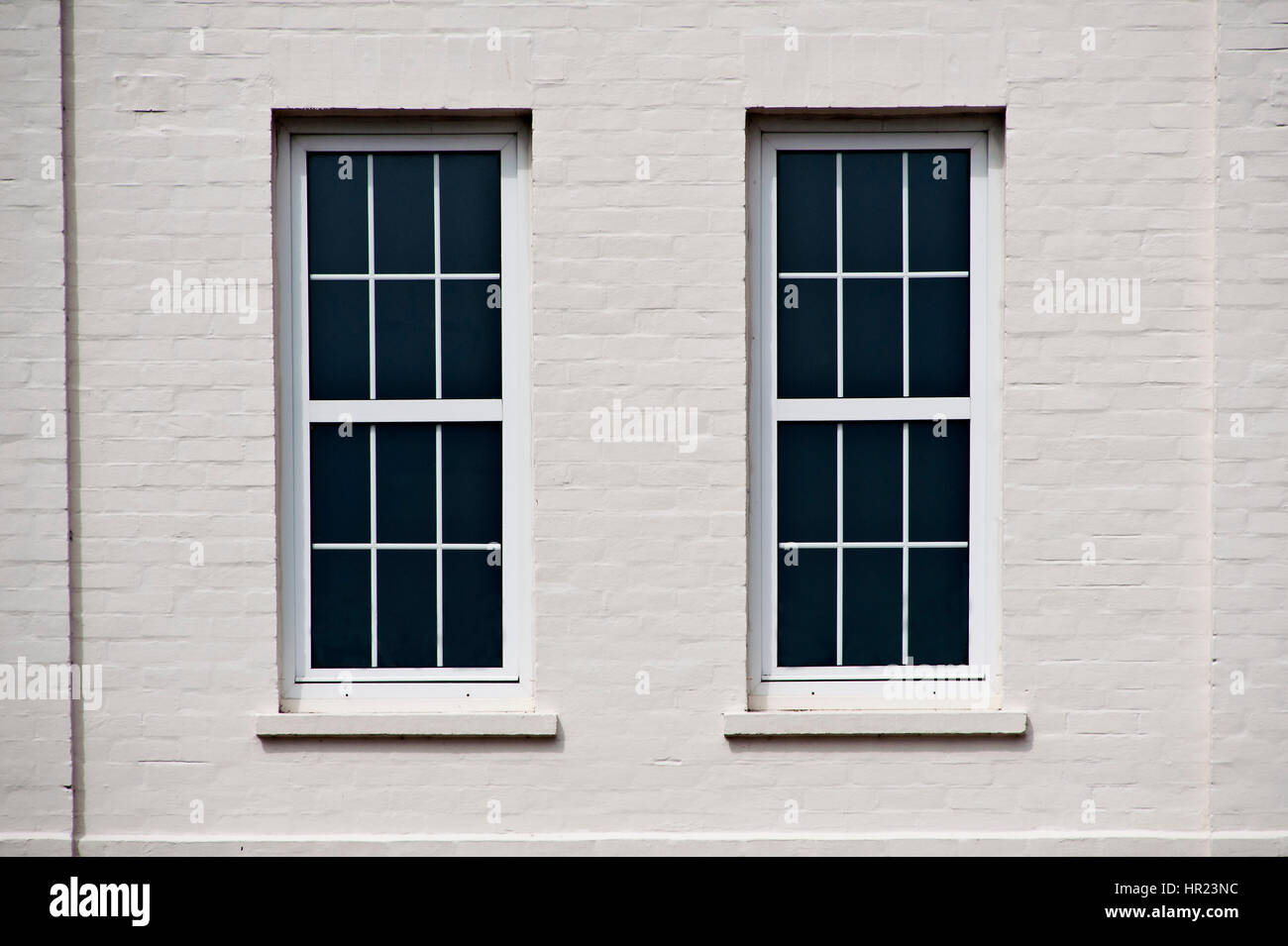Two large sash windows in a white-painted wall of a historic building Stock Photo