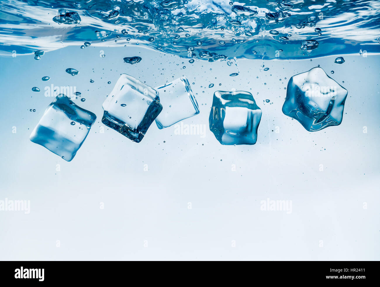 Ice cubes falling into the water sinking to the bottom. Abstract background. Stock Photo