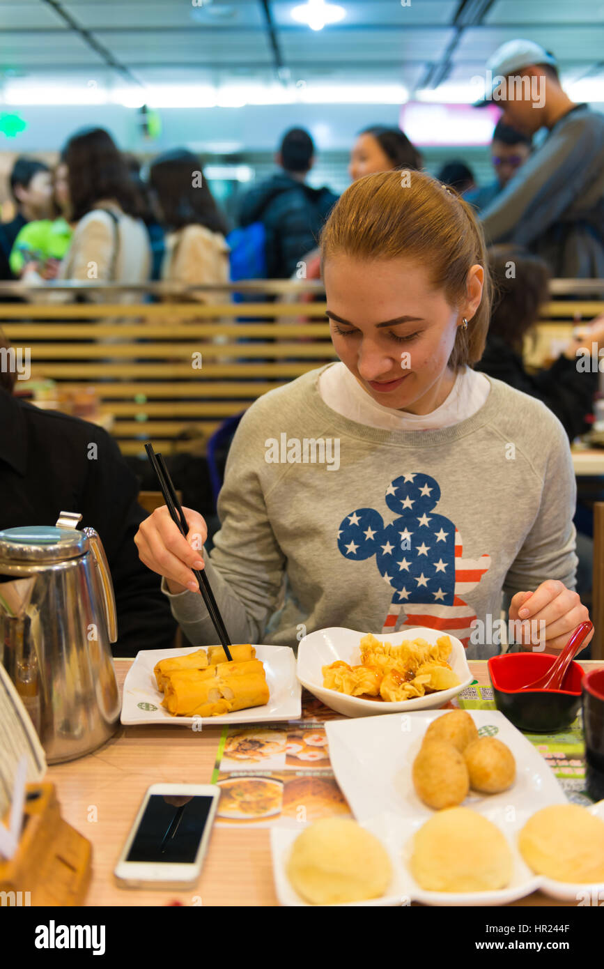Girl eats dim sum and spring rolls in Michelin star fast food restaurant in Hong Kong Stock Photo