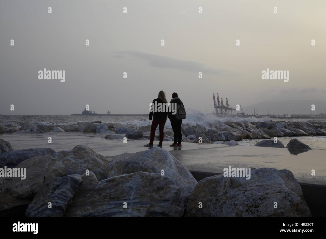 Two girls looking at big waves in the beach of Malaga. Stock Photo