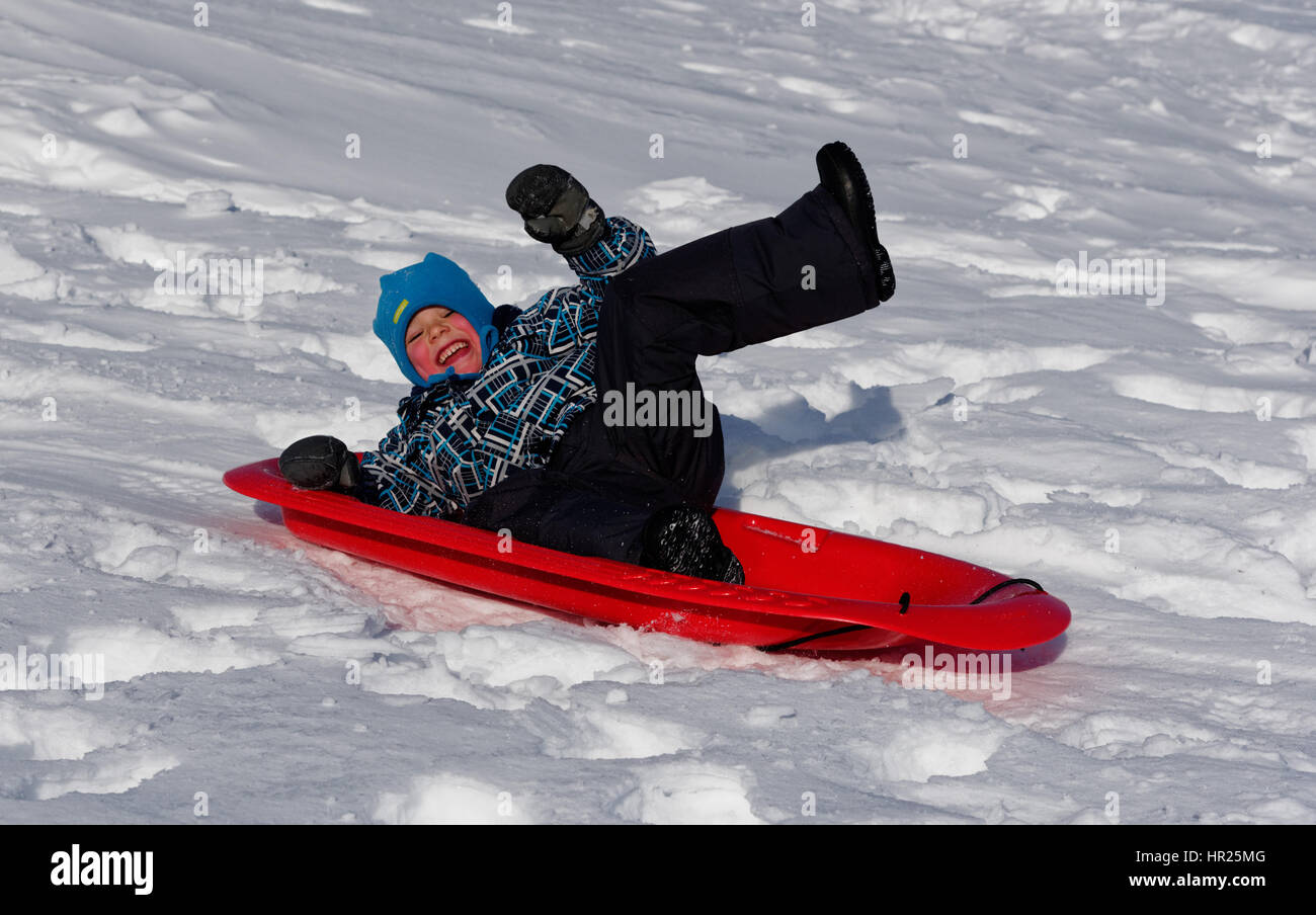 A young Boy (4 yrs old) jumping into the air on a sledge in Quebec winter Stock Photo