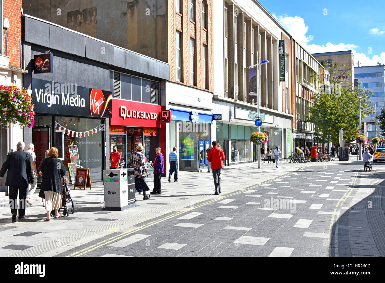 Shoppers high street retail shopping area in town centre Slough Berkshire UK pavedover road