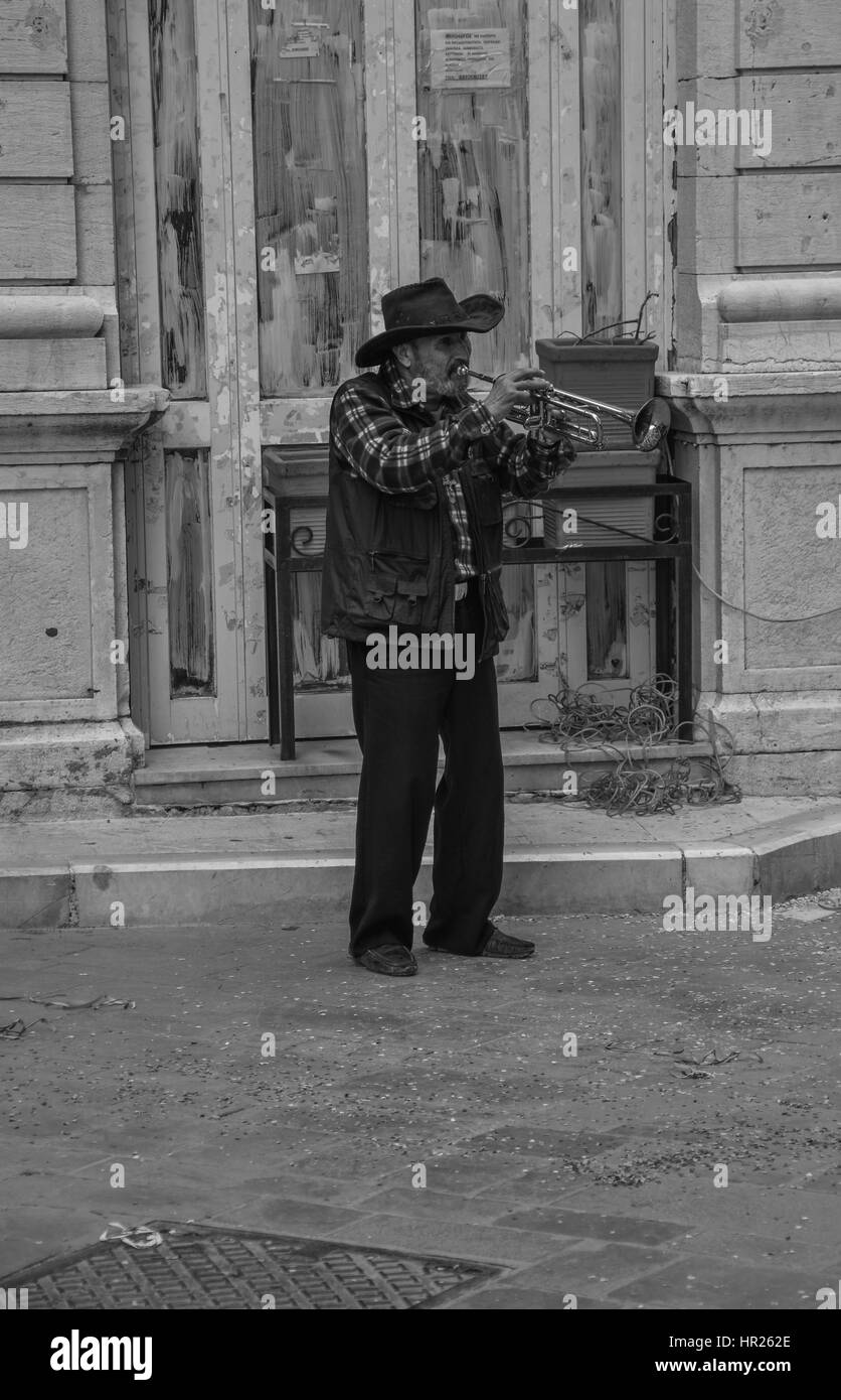 Old man playing his trumpet on the streets of Corfu Town, Greece. IN black and white Stock Photo