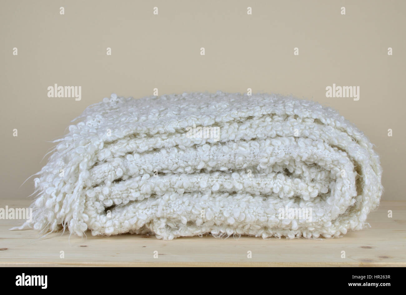 White soft woolen blanket with cozy look on wooden shelf Stock Photo