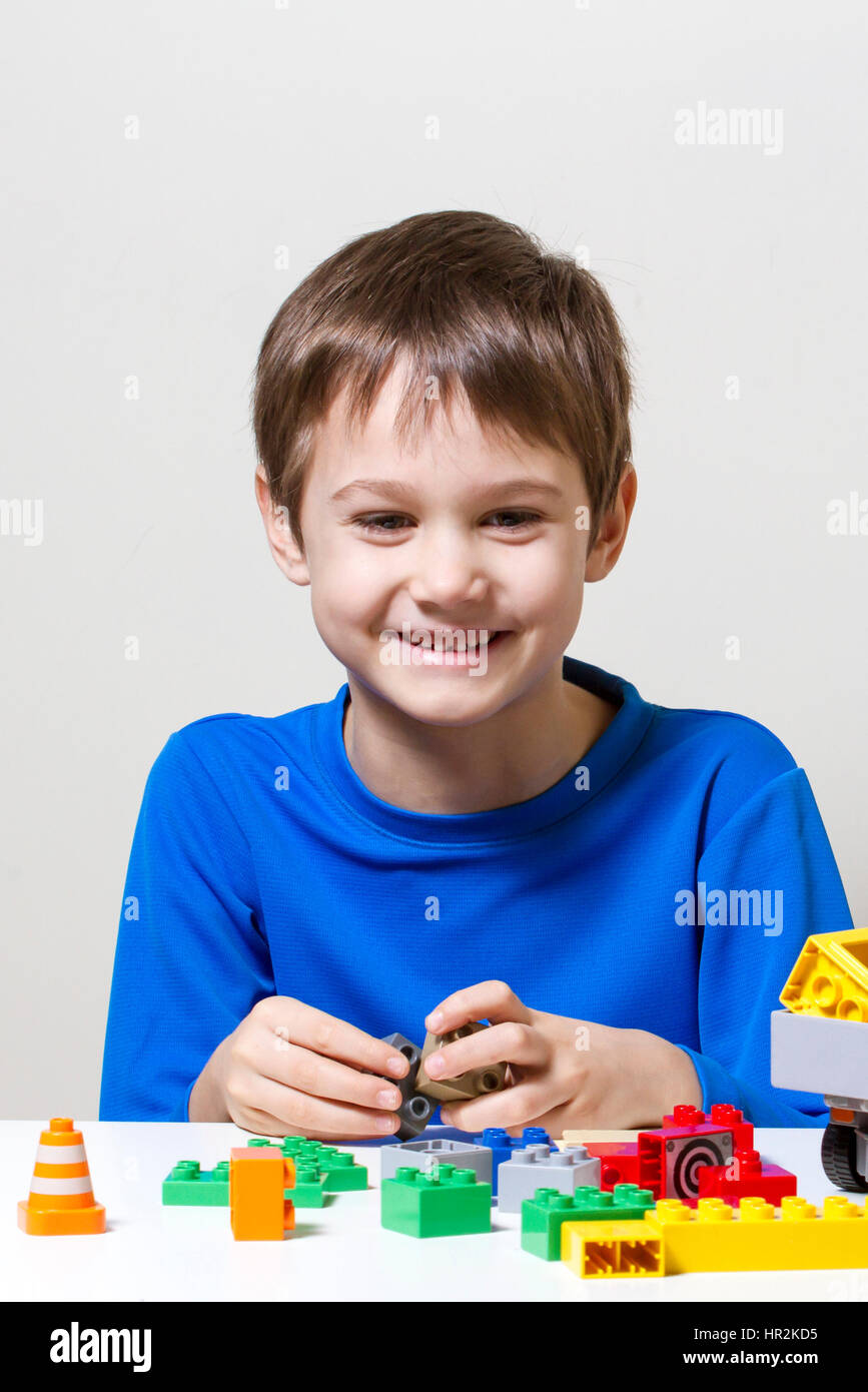 Happy kid playing with colorful plastic construction toy blocks at the ...