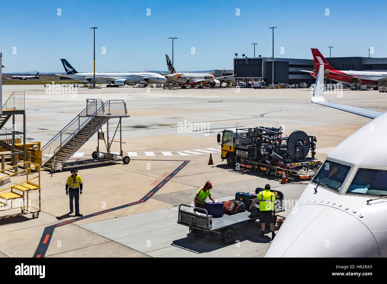 Baggage handlers prepare to start loading luggage ontp airplane. Stock Photo