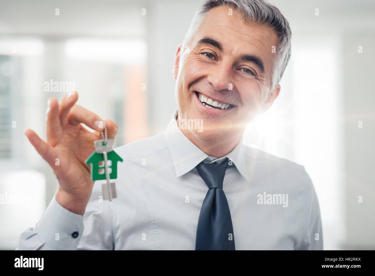 Confident real estate agent holding your new house keys and smiling at ...
