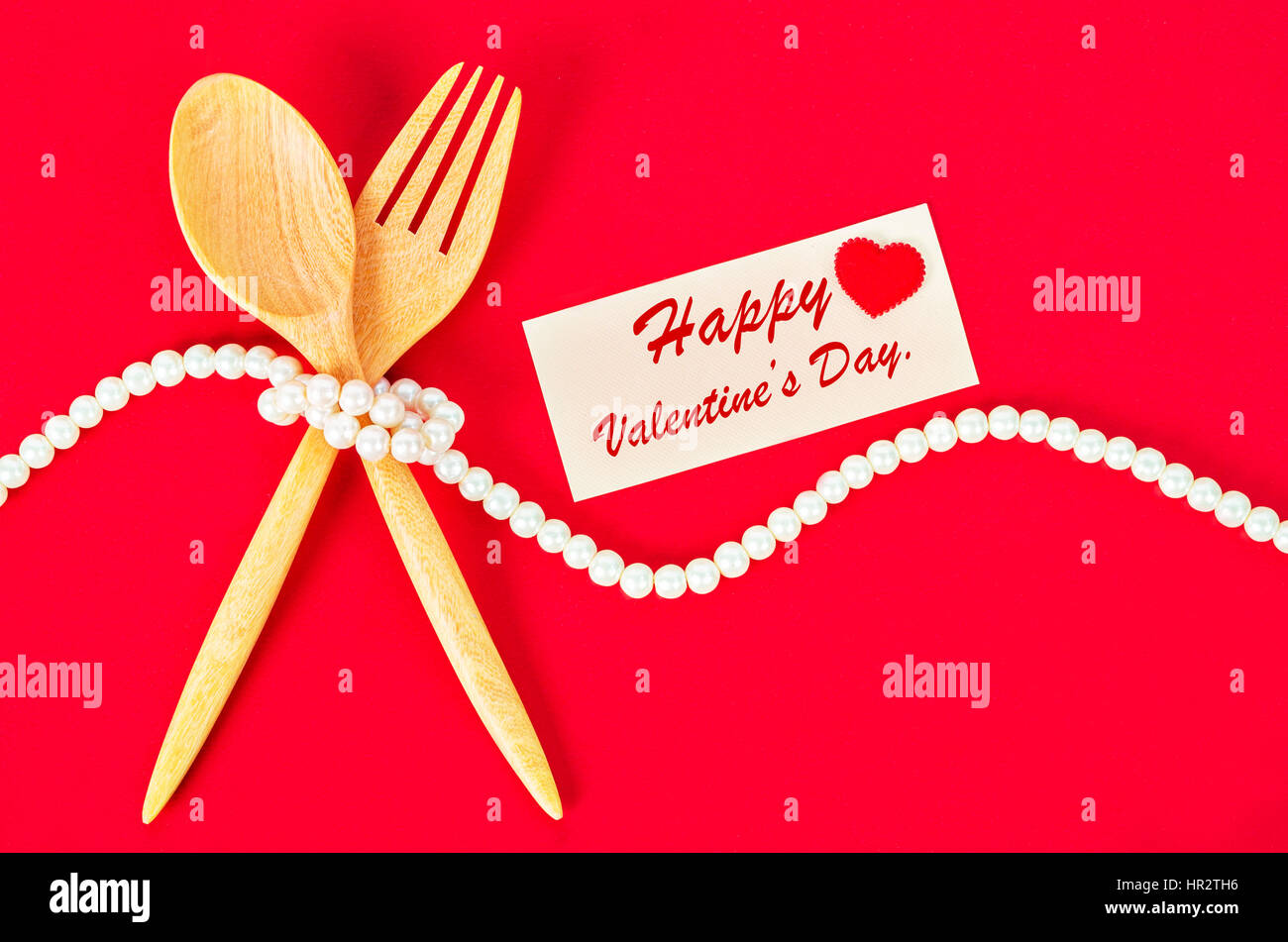 Wooden spoon and fork with blank greeting card for valentine on red