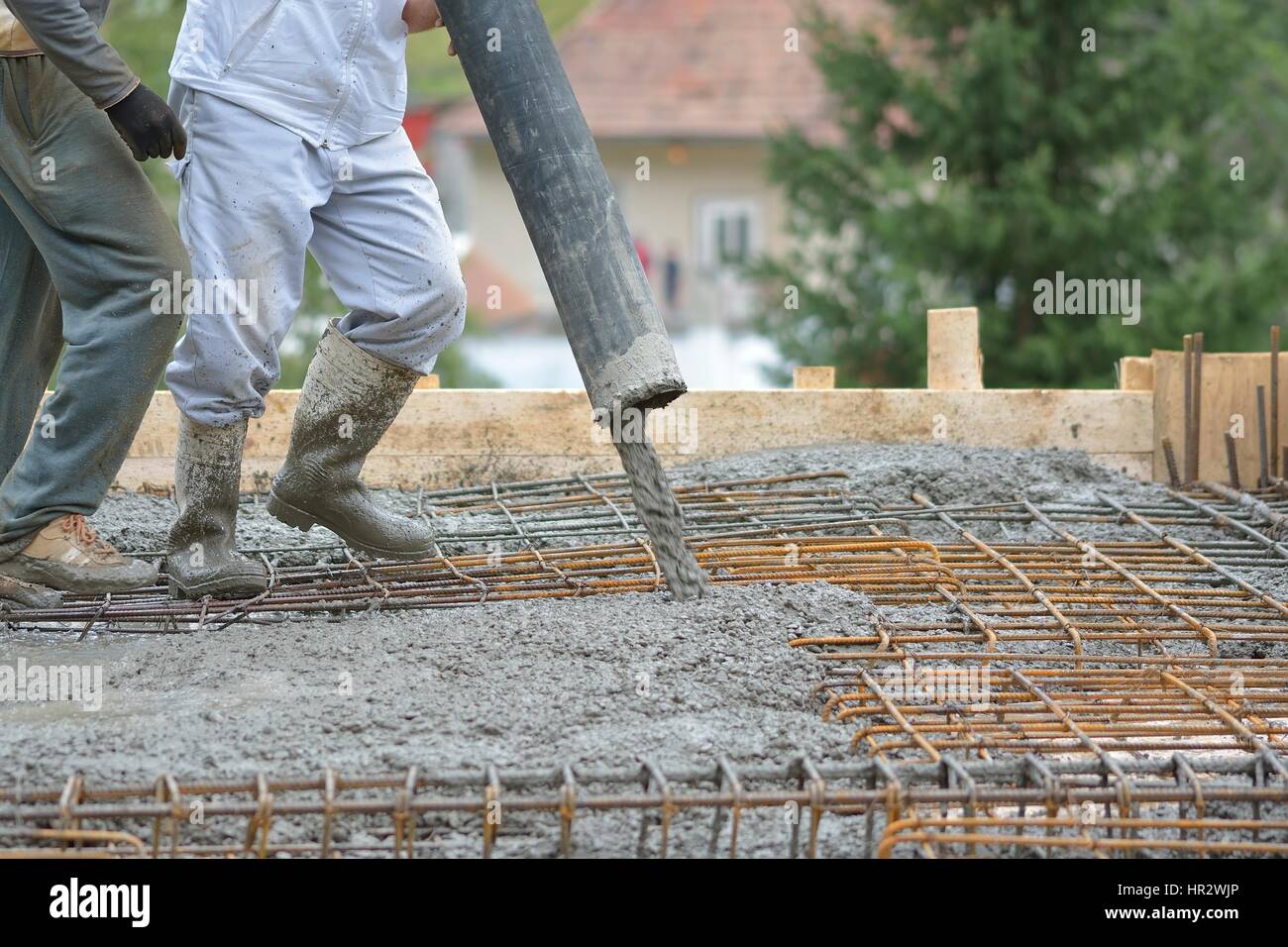 building construction worker pouring cement or concrete with pump tube