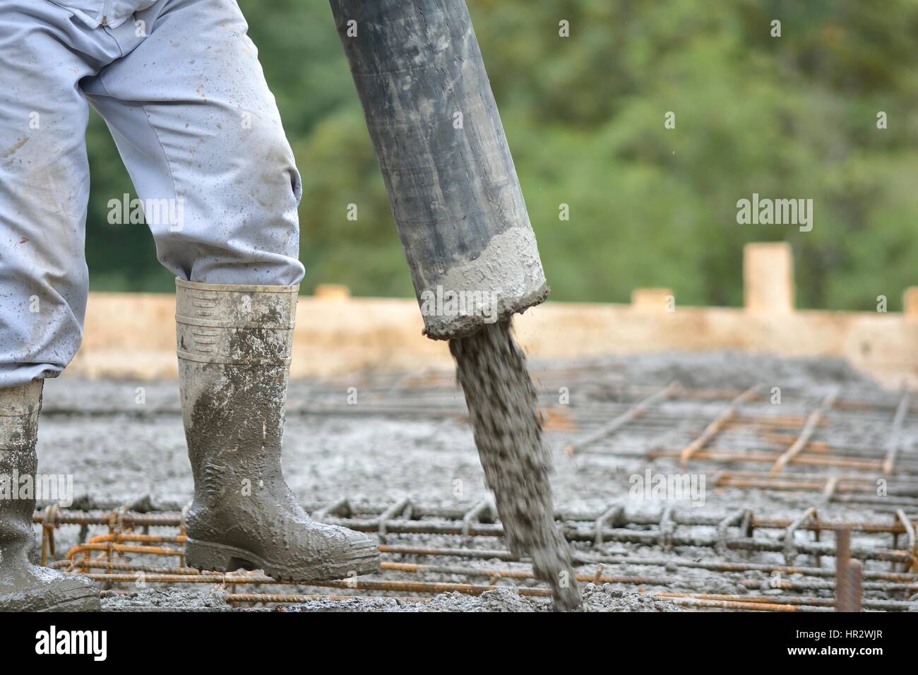 building construction worker pouring cement or concrete with pump tube