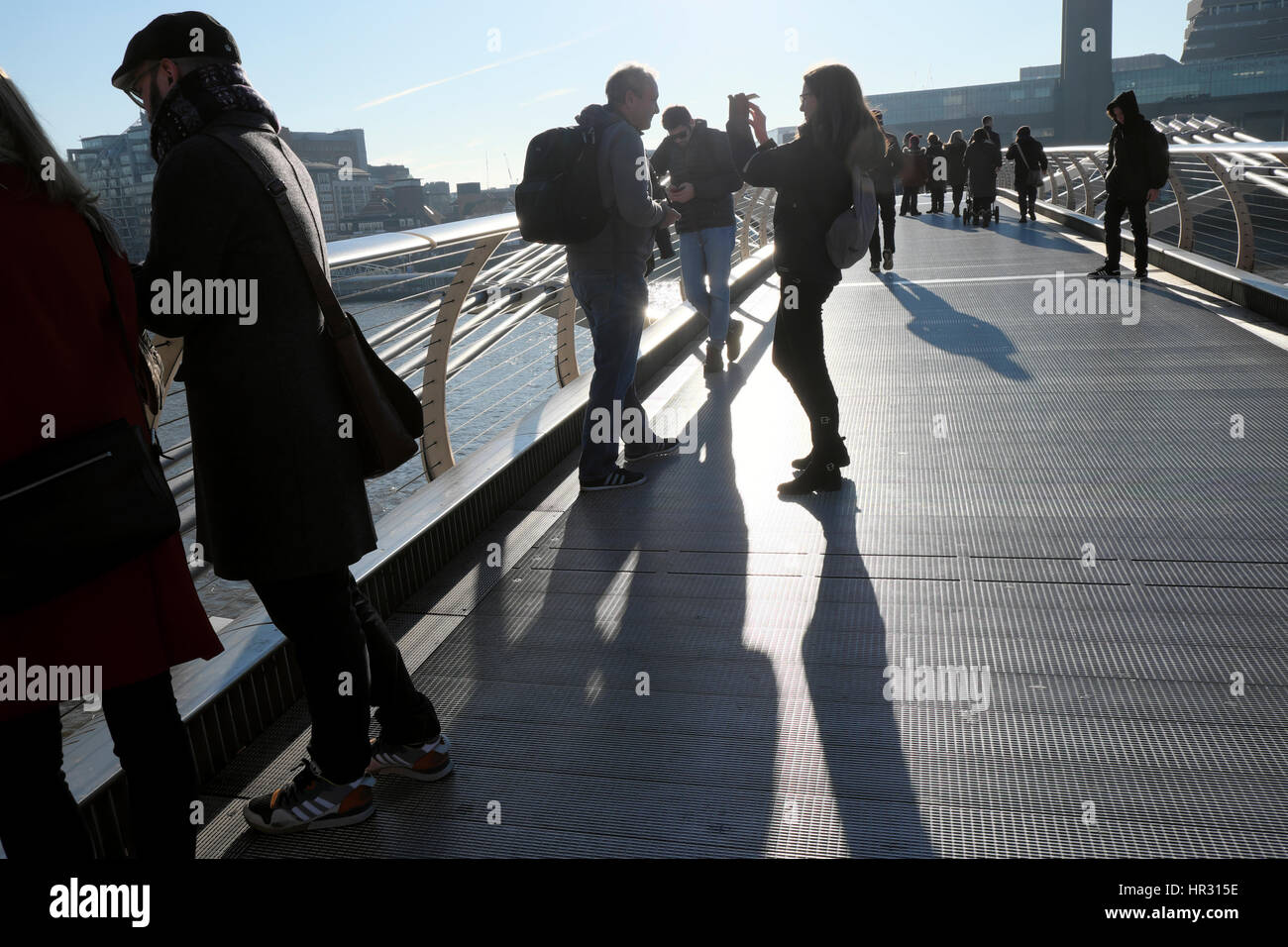 People enjoying a sunny winter day on the Millennium Bridge in London England UK  KATHY DEWITT Stock Photo