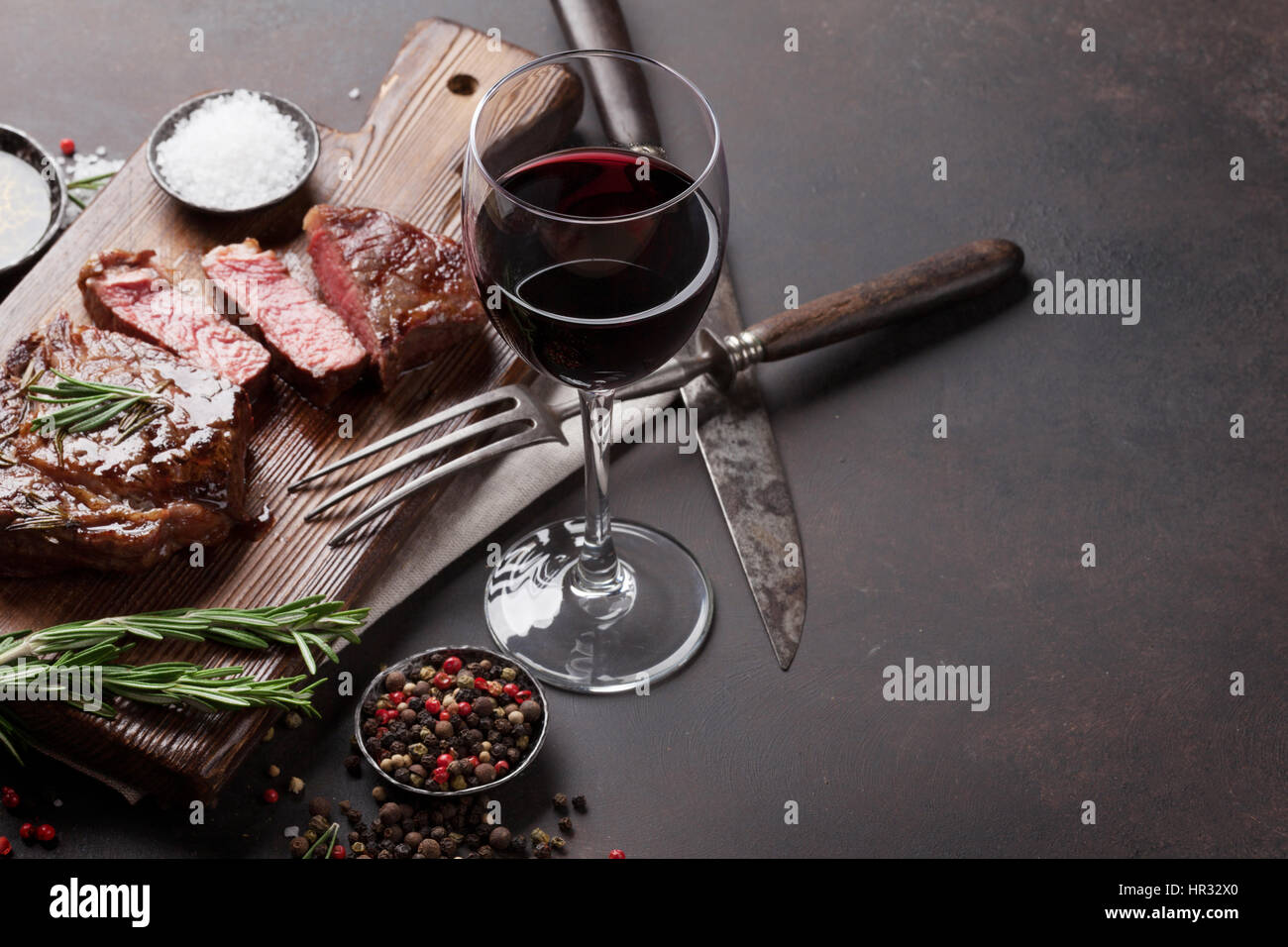 Grilled ribeye beef steak with red wine, herbs and spices on stone ...
