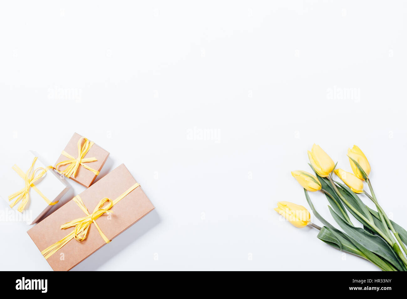 Top view of yellow tulips and gift boxes with ribbons on white ...