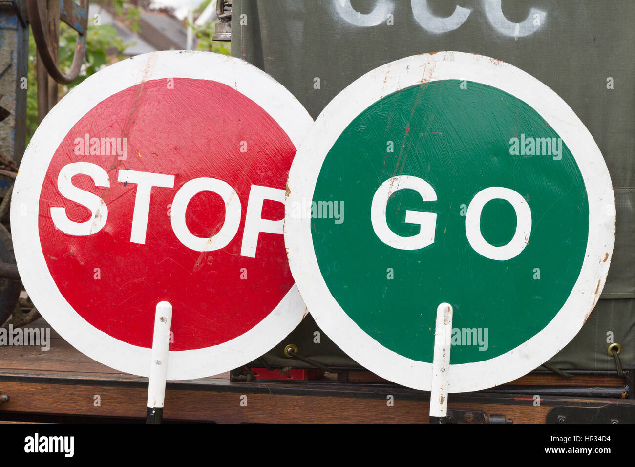 Hand-held, hand-painted vintage 'Stop' and 'Go' lollipop traffic signs. Indicates indecision, mixed messages, ambiguity. Stock Photo