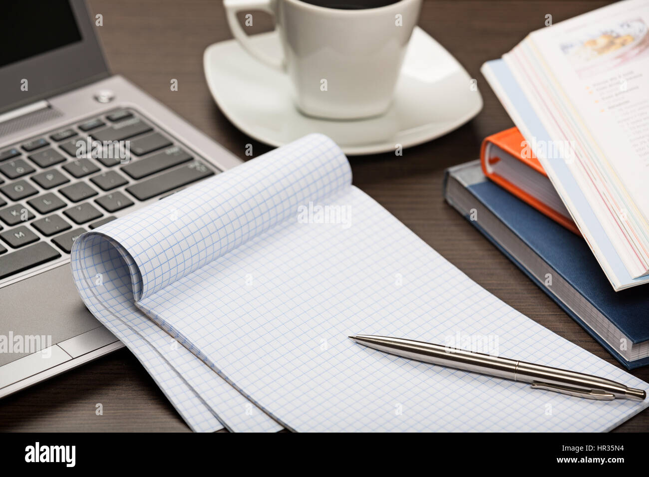 Notepad, pen, books, laptop and cup of coffee on dark wooden office desk  Stock Photo - Alamy