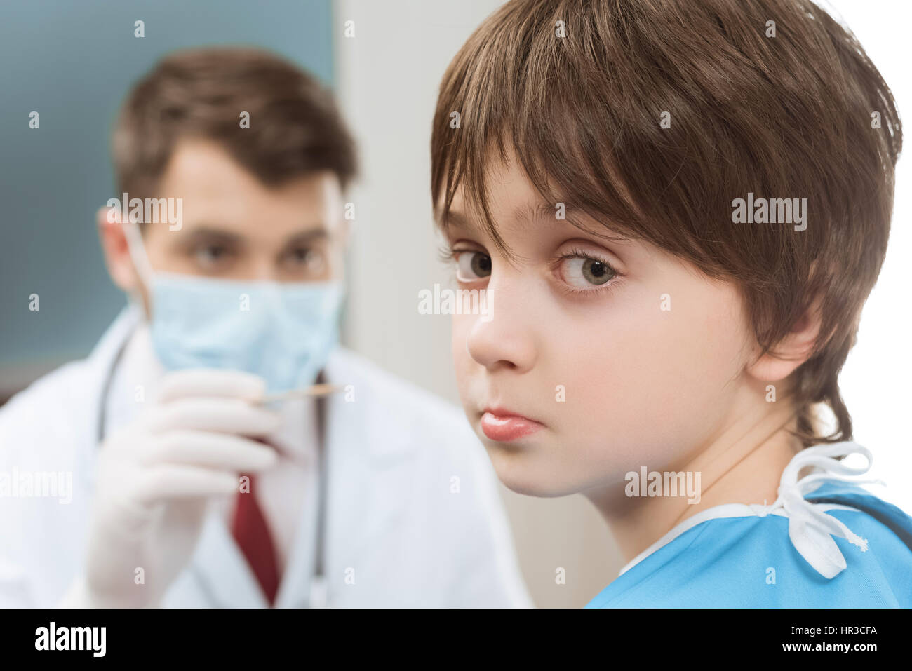 boy looking at camera while doctor going to examine throat Stock Photo