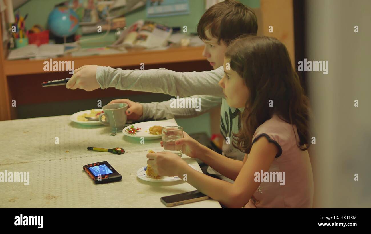 boy and a girl changes channels TV remote control watch, drink tea and eat cake Stock Photo