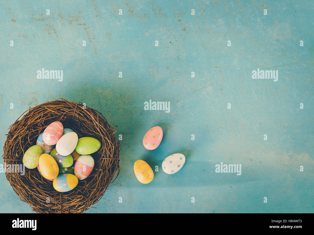 Colorful easter eggs in nest on blue wood background with copy space ...