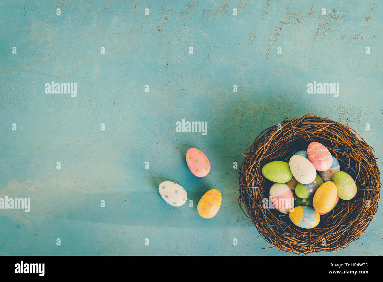 Colorful easter eggs in nest on blue wood background with copy space ...