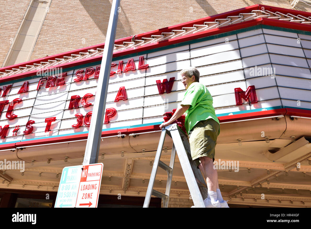 Female senior citizen changing a theater marquee sign in Abilene Texas. Stock Photo