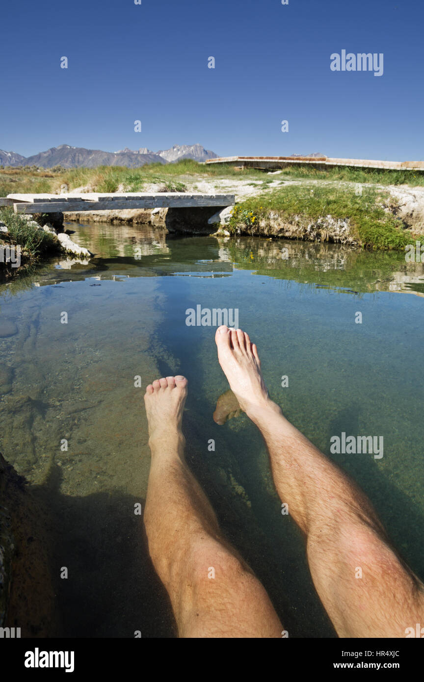 a mans legs soaking in a hot spring in the Eastern Sierra of California Stock Photo