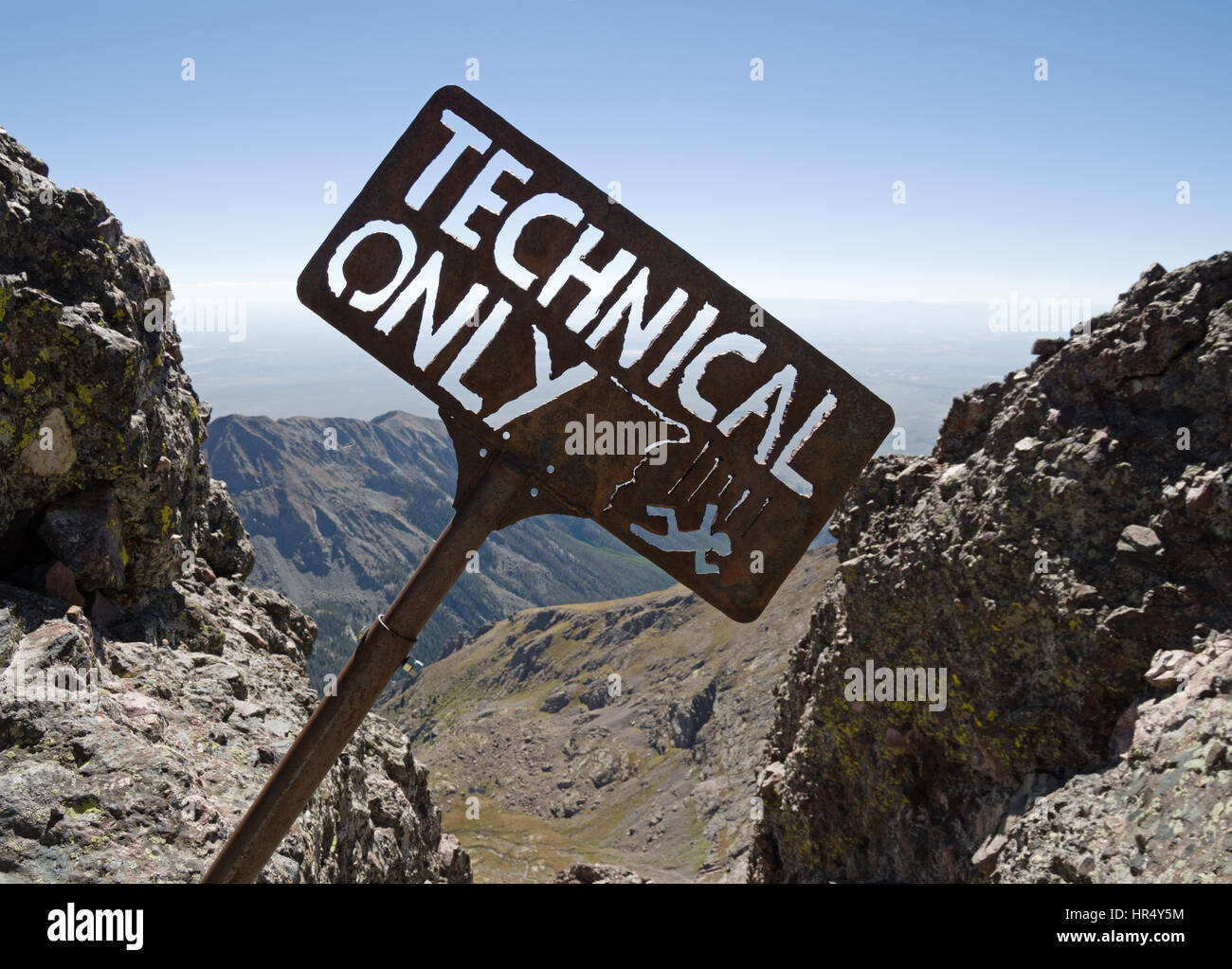 technical only sign with falling climber above a steep cliff on Crestone Needle Peak Stock Photo