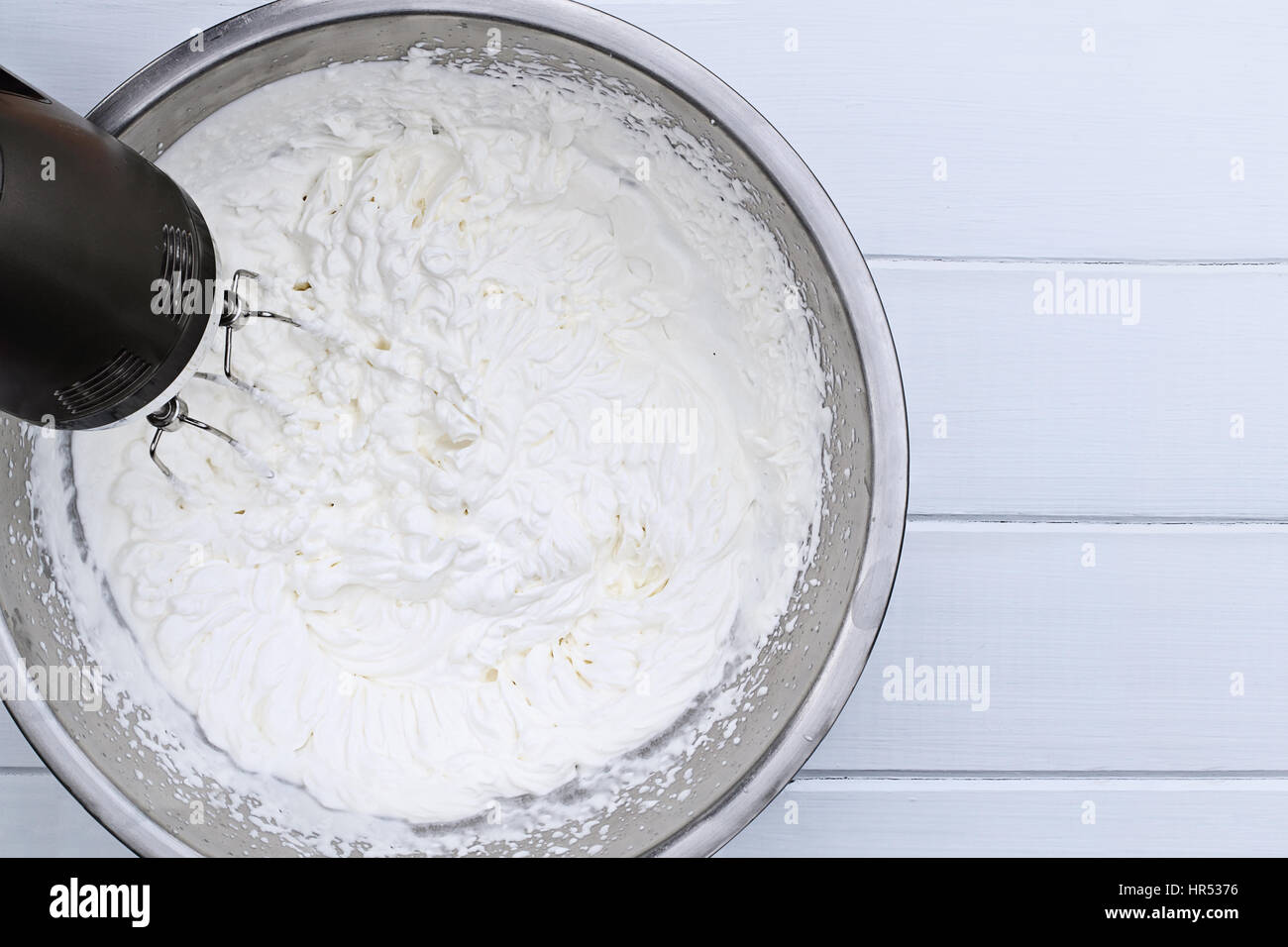 Beating a white cream with a mixer in a metal bowl. Whipped cream. Cream  for the cake Stock Photo - Alamy