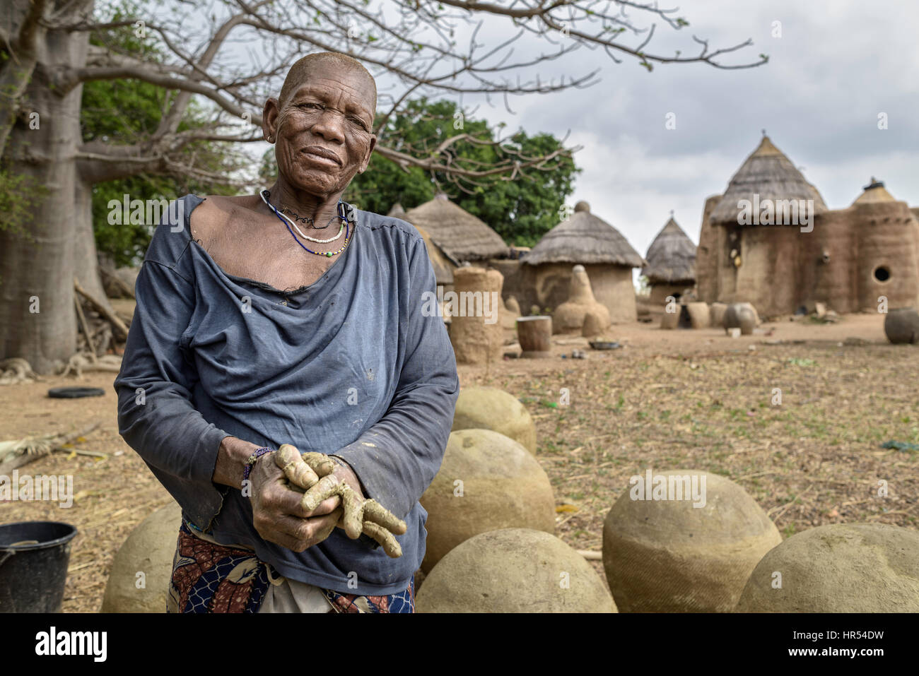 Old woman from the Tata Somba tribe making clay pots nearby her traditional house also made with mud and straws. Stock Photo