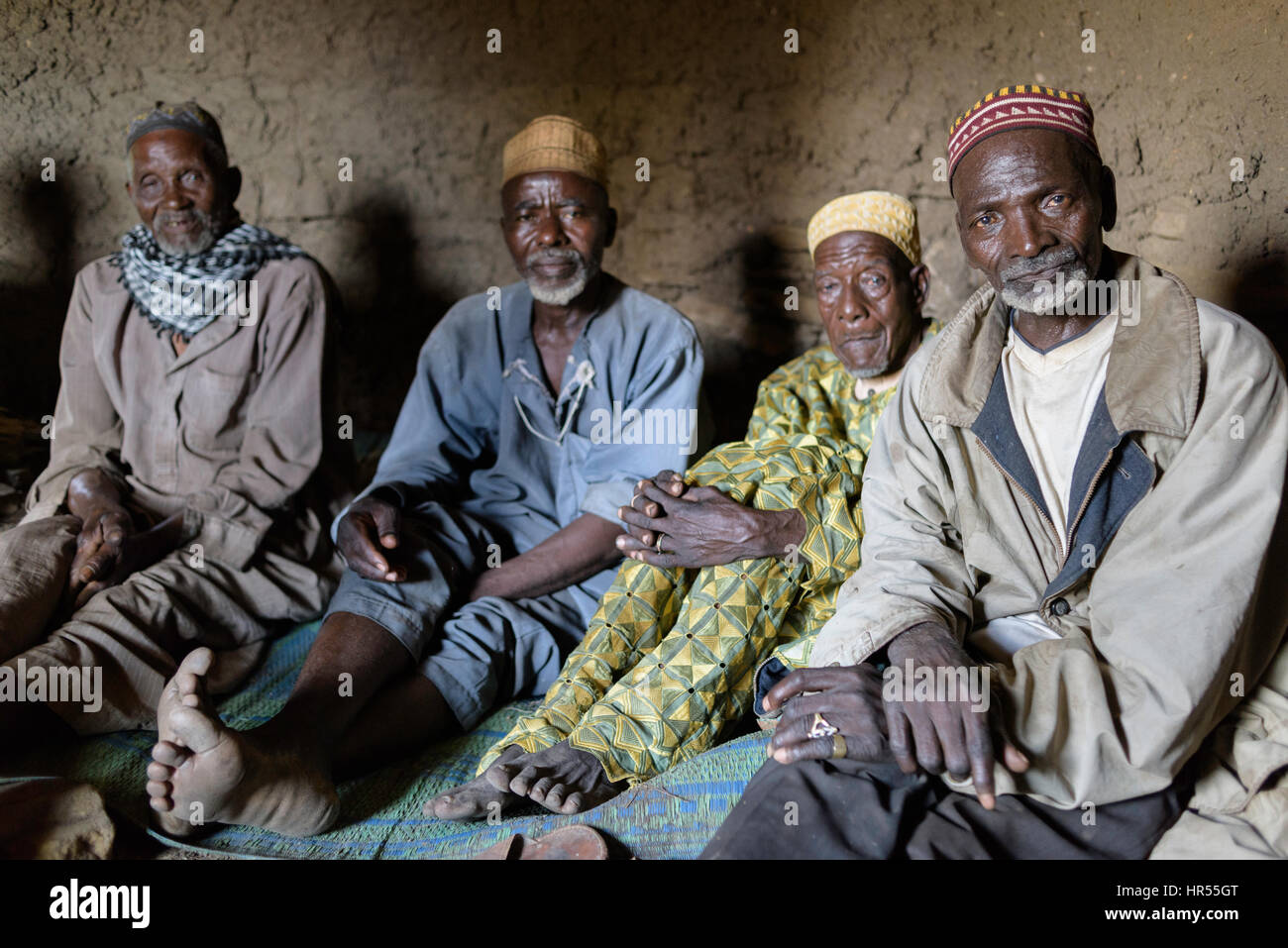 Group of the elders of Yaka inside the hut where the keep the knifes for the circumcision ceremony. They are the ones in charge of organising  the cer Stock Photo