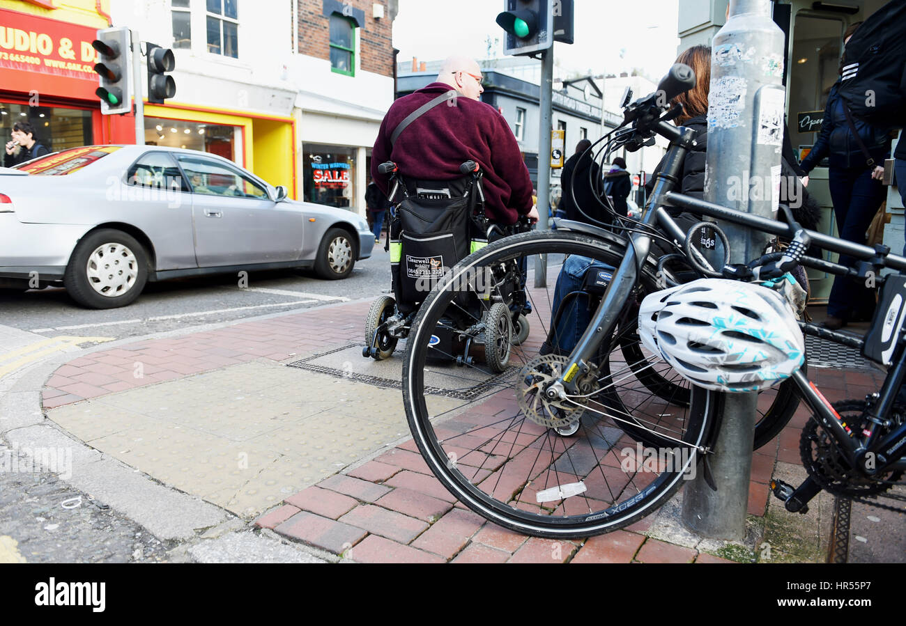 Wheelchair user has trouble getting by a chained bicycle on pavement in Brighton UK Stock Photo