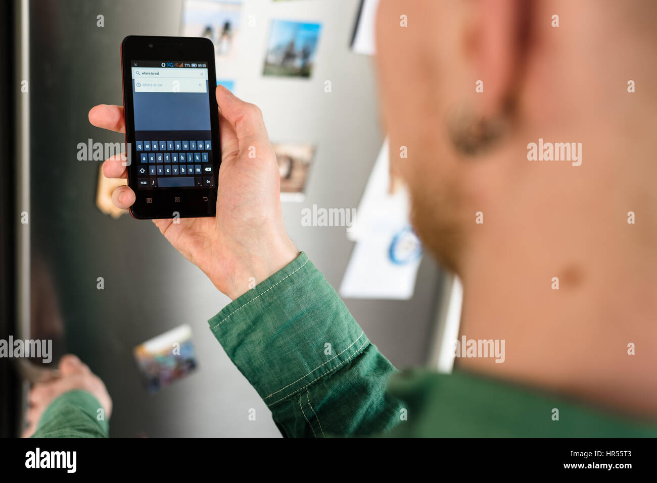 Close-up of person hands holding smartphone showing web browser search tool with virtual keyboard on screen and searching online for places to eat. Re Stock Photo