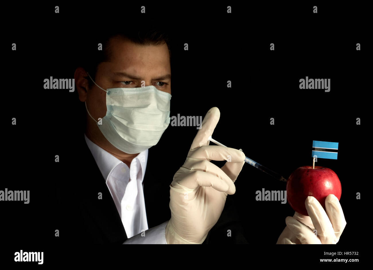 Young businessman injecting chemicals into an apple with Botswanan flag on black background Stock Photo