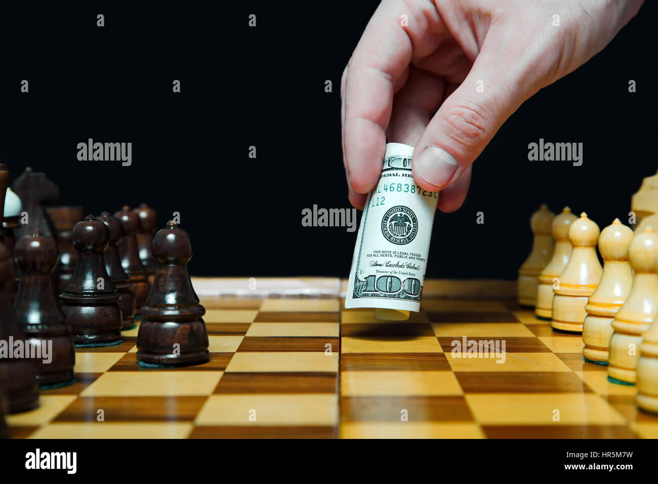Man plays chess with hundred dollars bill and makes move Stock Photo