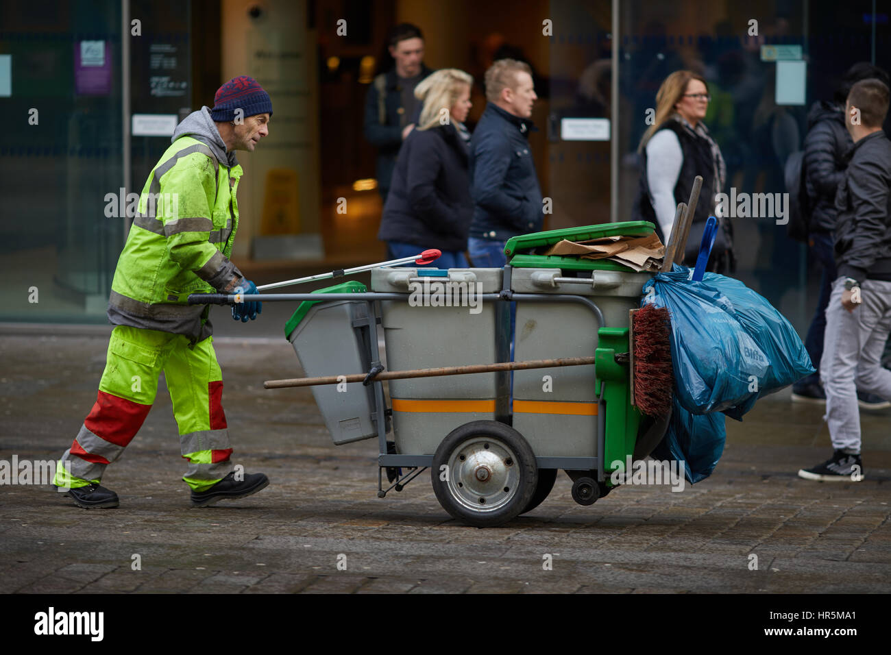 Council bin emptying with hand cart pushed down Manchester, Market Street, England,UK. Stock Photo
