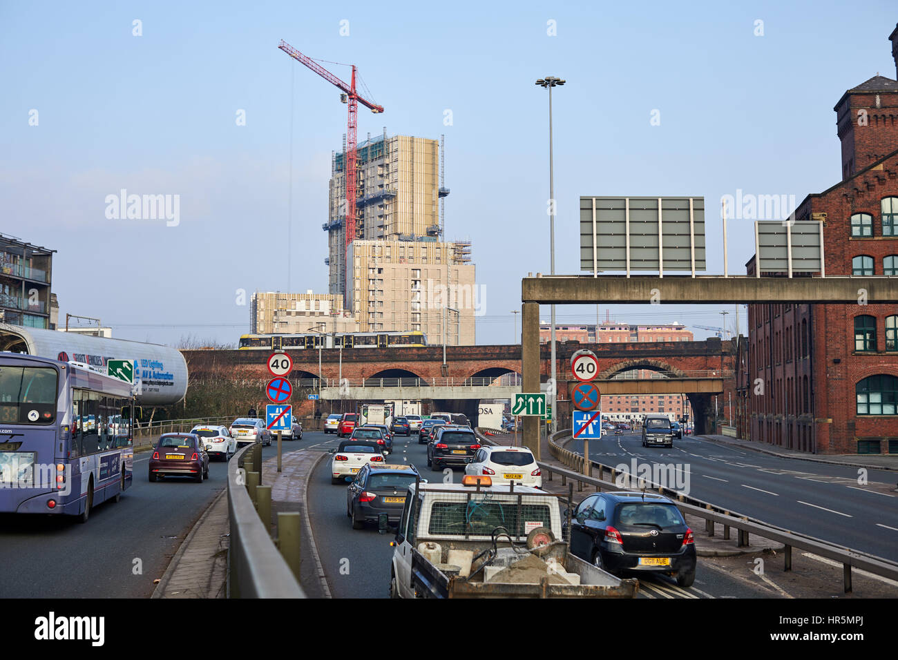 A yellow  Metrolink tram crossing a viaduct at  The Mancunian Way at  Castlefield Salford boundary Manchester England,UK Stock Photo