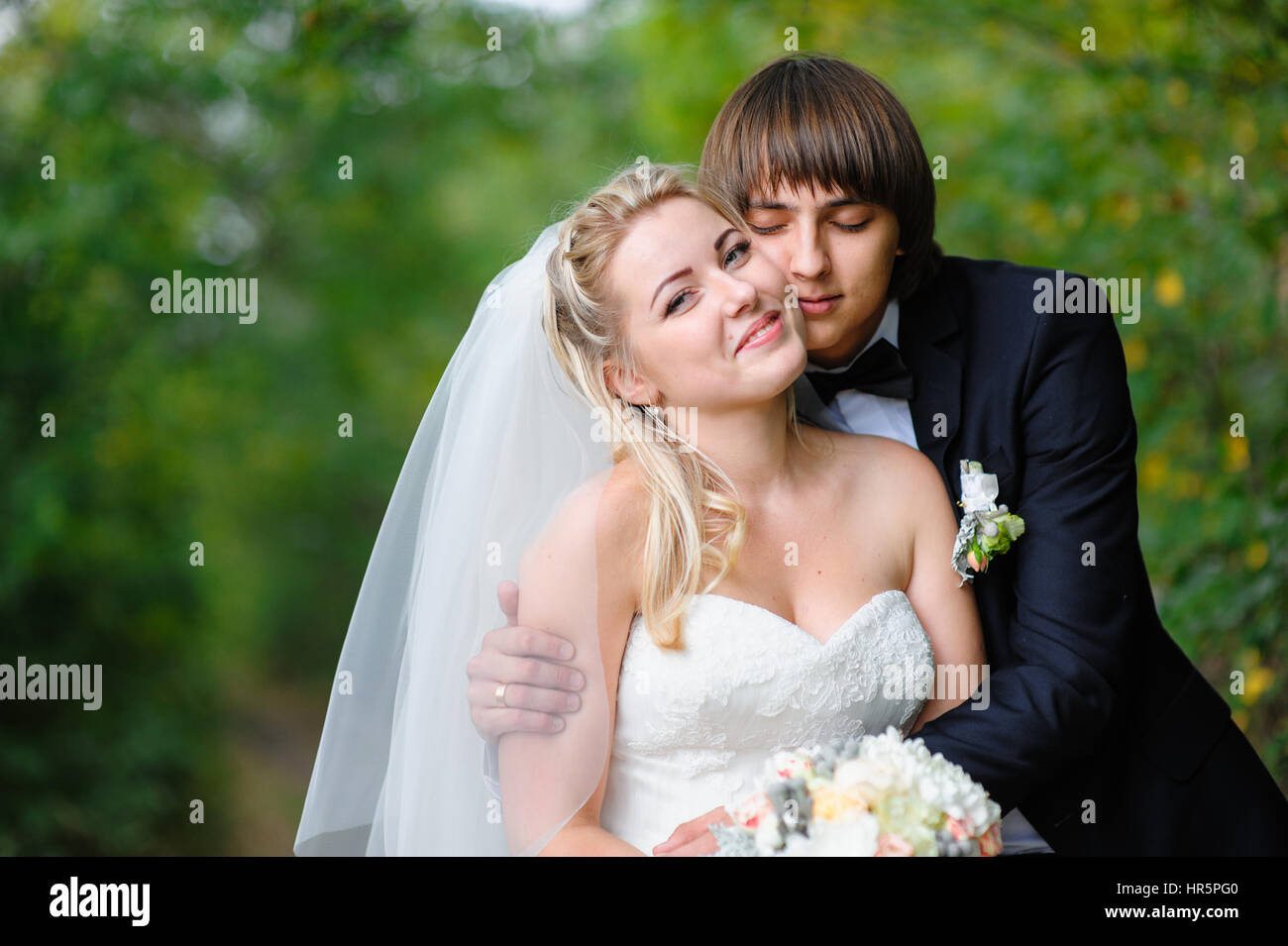 Groom hugs bride on walk in the summer park Stock Photo - Alamy
