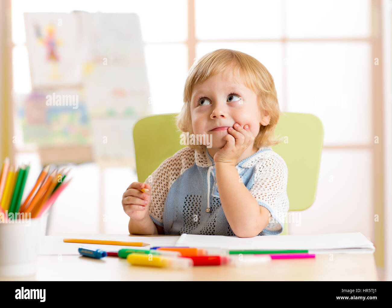Smiling kid drawing with color pencils in daycare center Stock Photo