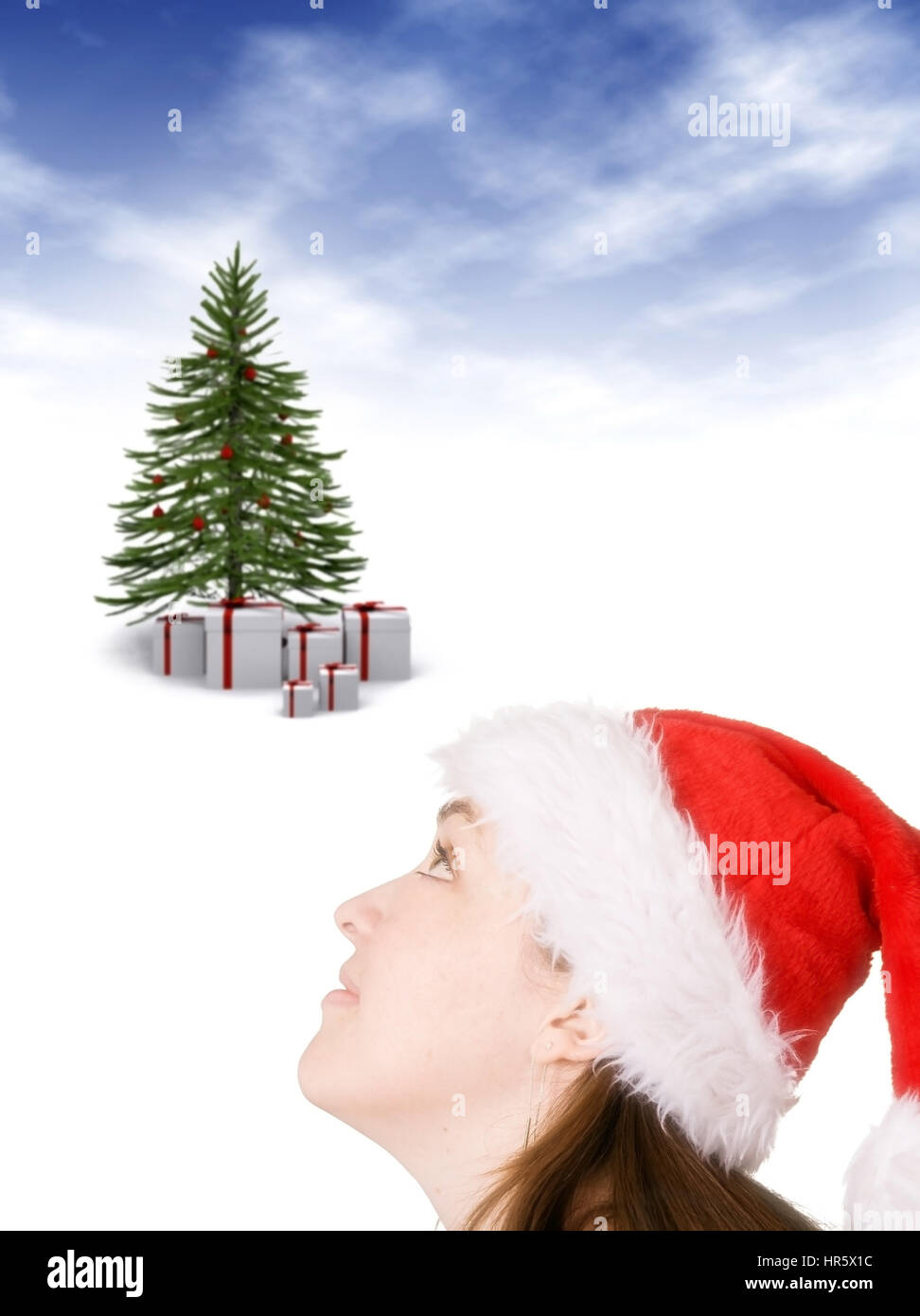 beautiful girl wearing a christmas hat looking up towards the christmas tree Stock Photo