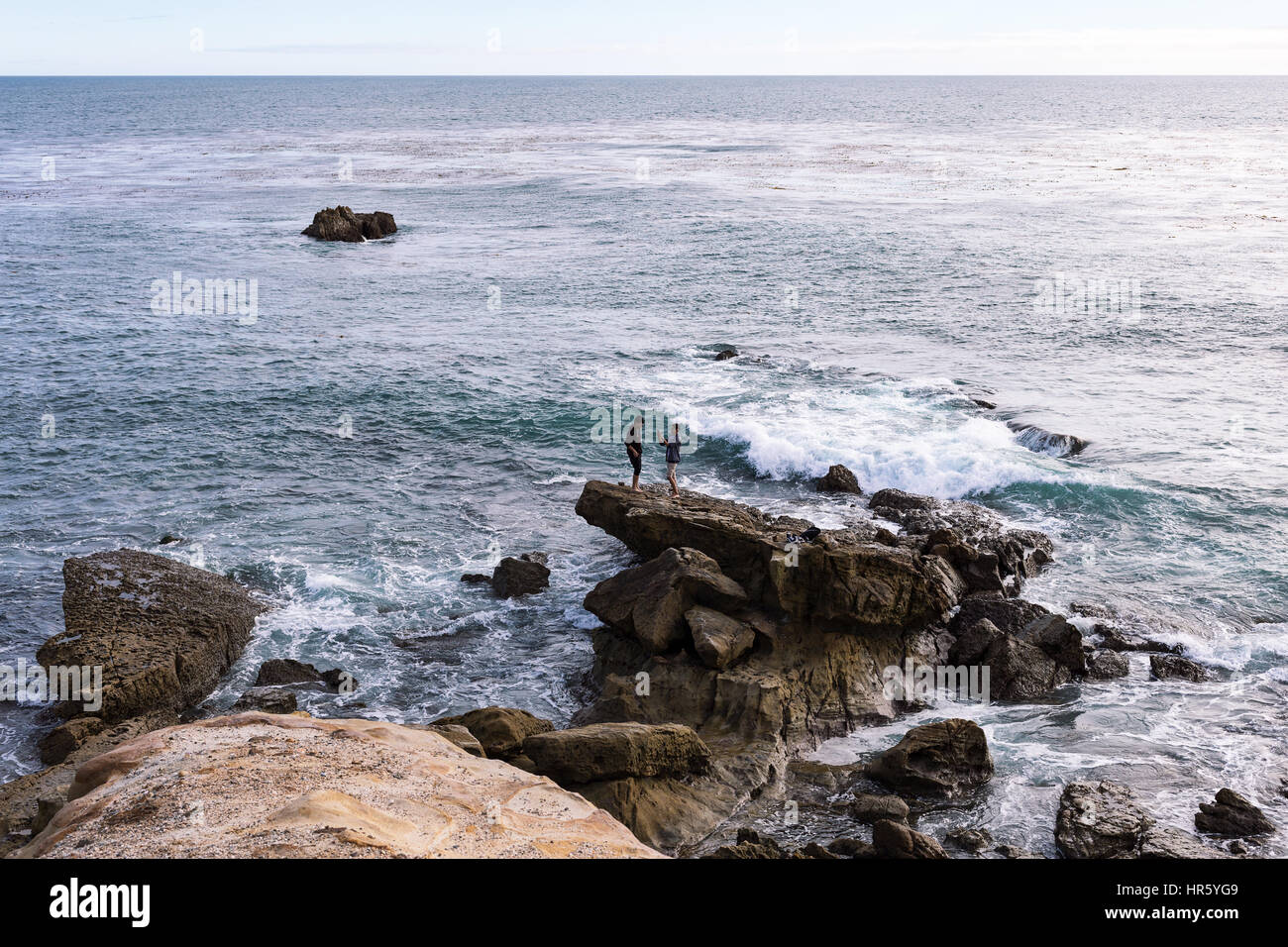Two young men taking cell phone photos by the ocean in Laguna Beach