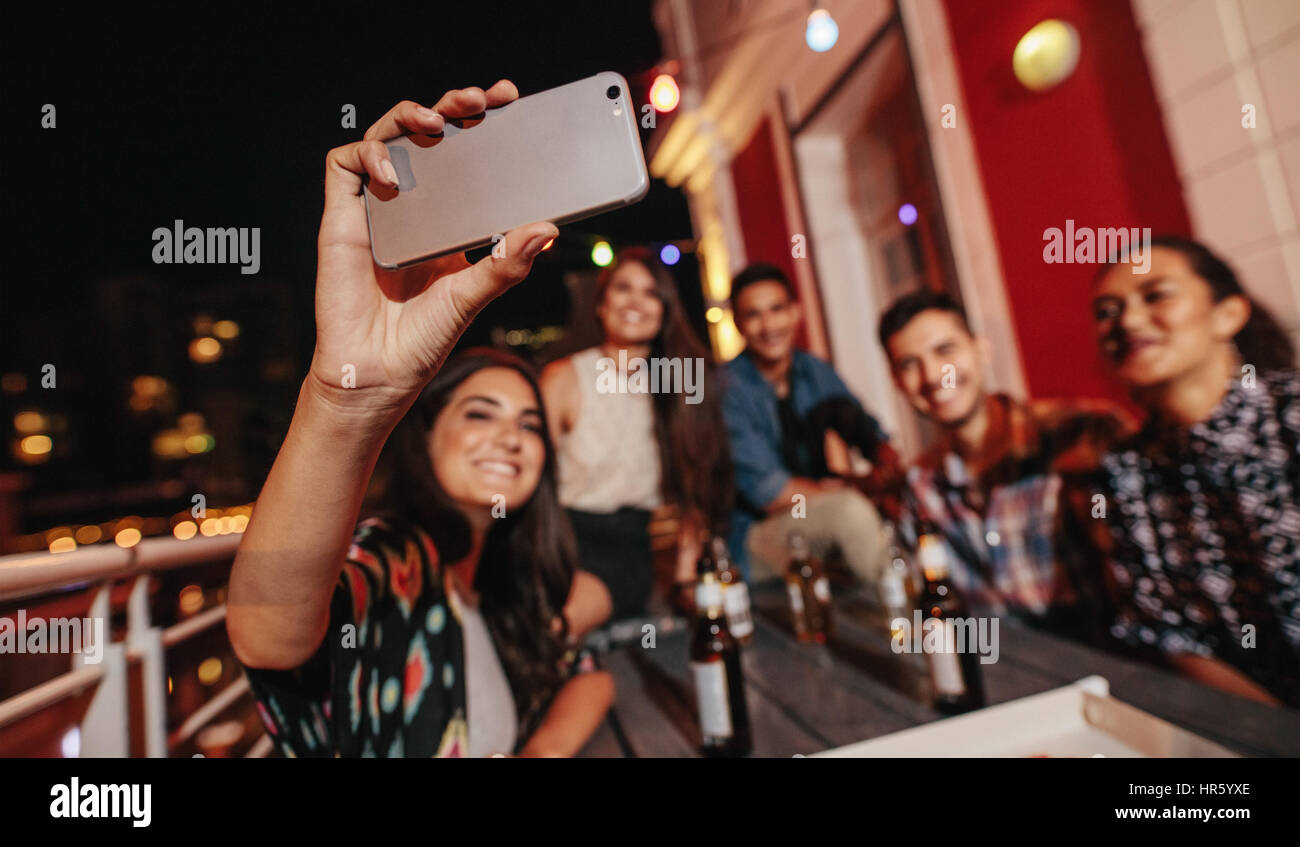 Friends having a party on the rooftop making a selfie with smart phone ...