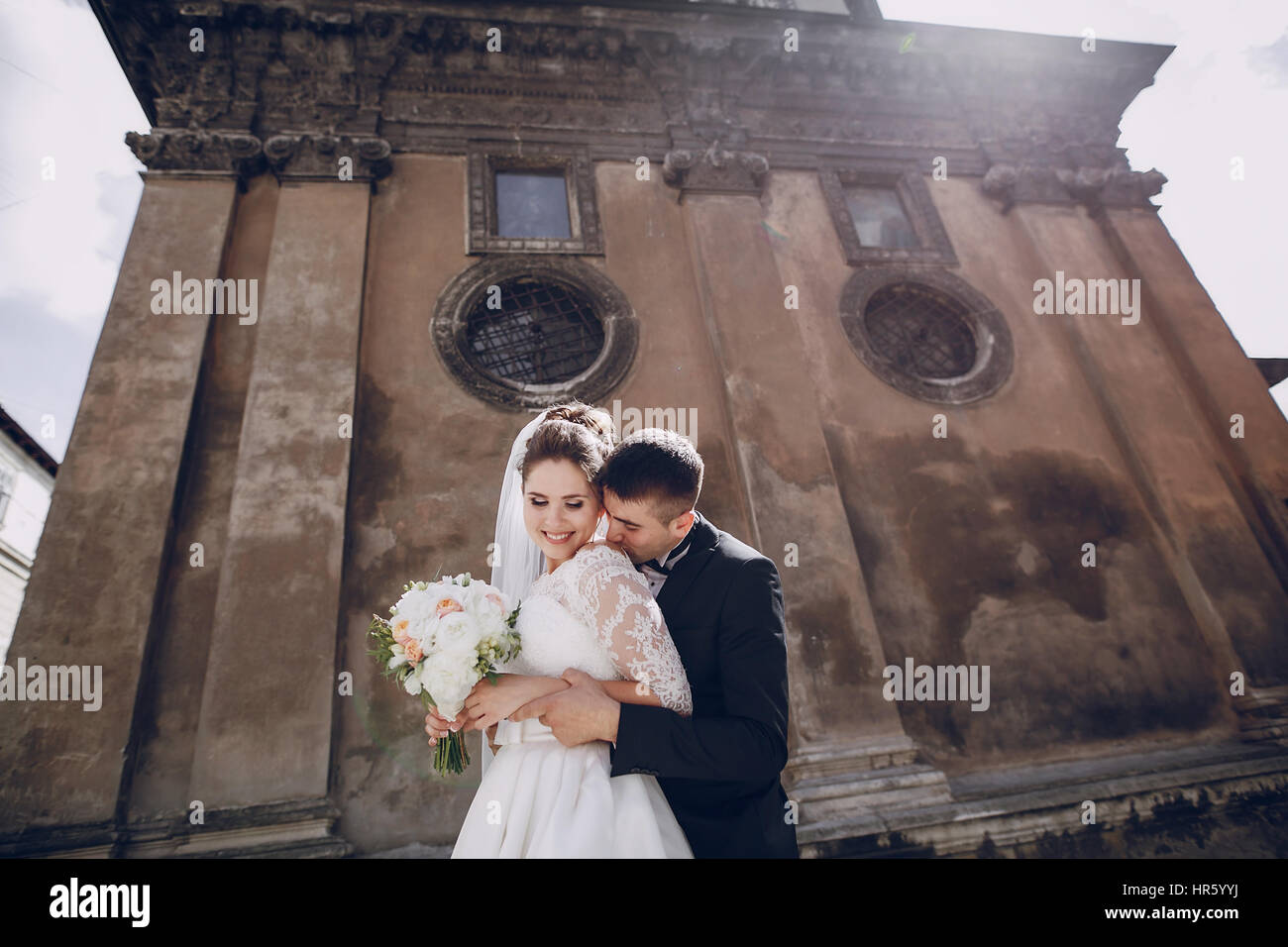 bride and groom standing near the old brown house Stock Photo - Alamy
