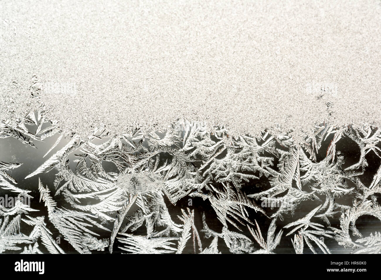 Frosted and frozen ice formations and patterns on a clear glass window ...