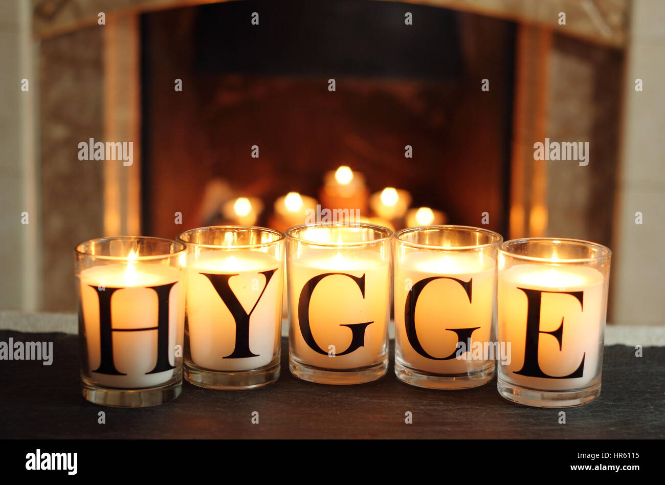 Fireside candles in an English living room in winter depict 'hygge' - the Danish concept of embracing cosy contentment and conviviality Stock Photo