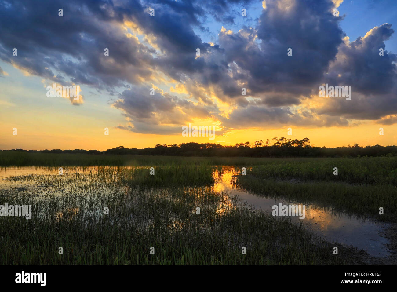 Summer storm clouds and a colorful sky hover over the marsh near the Kiawah River on Kiawah Island, South Carolina. Stock Photo