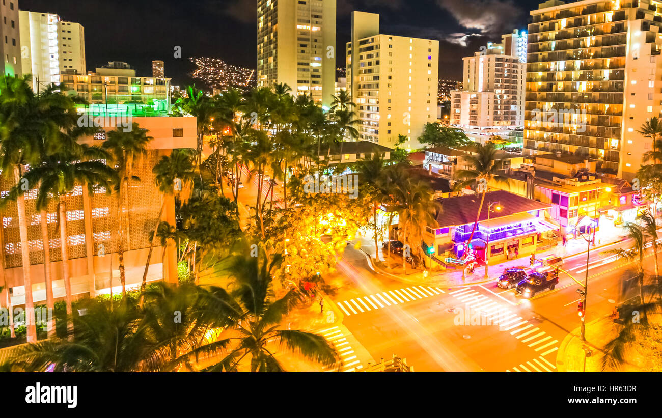 Aerial view night traffic of Waikiki city in Oahu, Hawaii, United States. Moving people and car glowing trails in the street. City night lights of sho Stock Photo