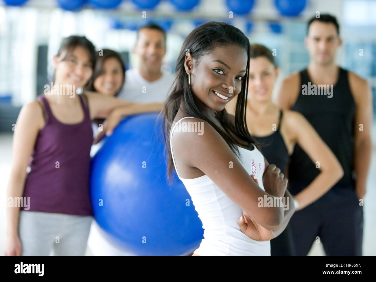Beautiful black woman smiling at the gym with her friends behind her ...