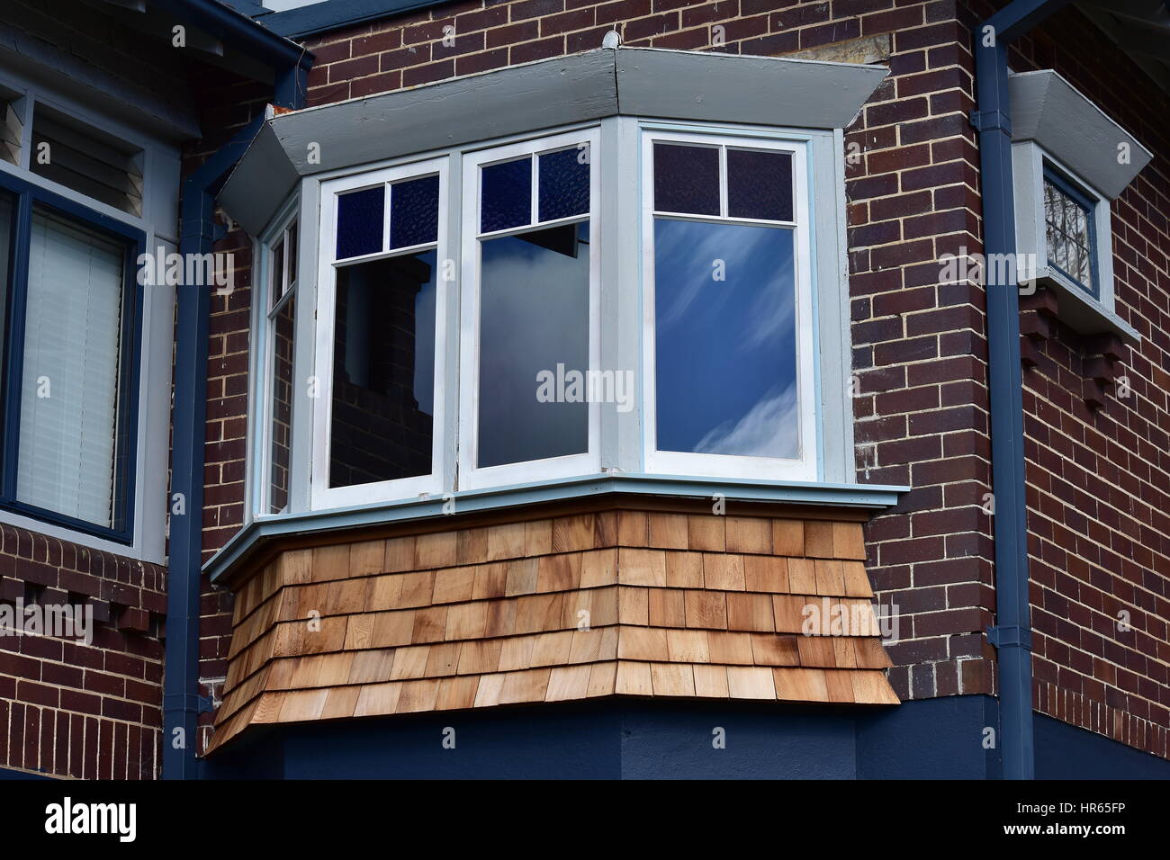 Multi-pane window with shingle cladding under it on brick house. Stock Photo