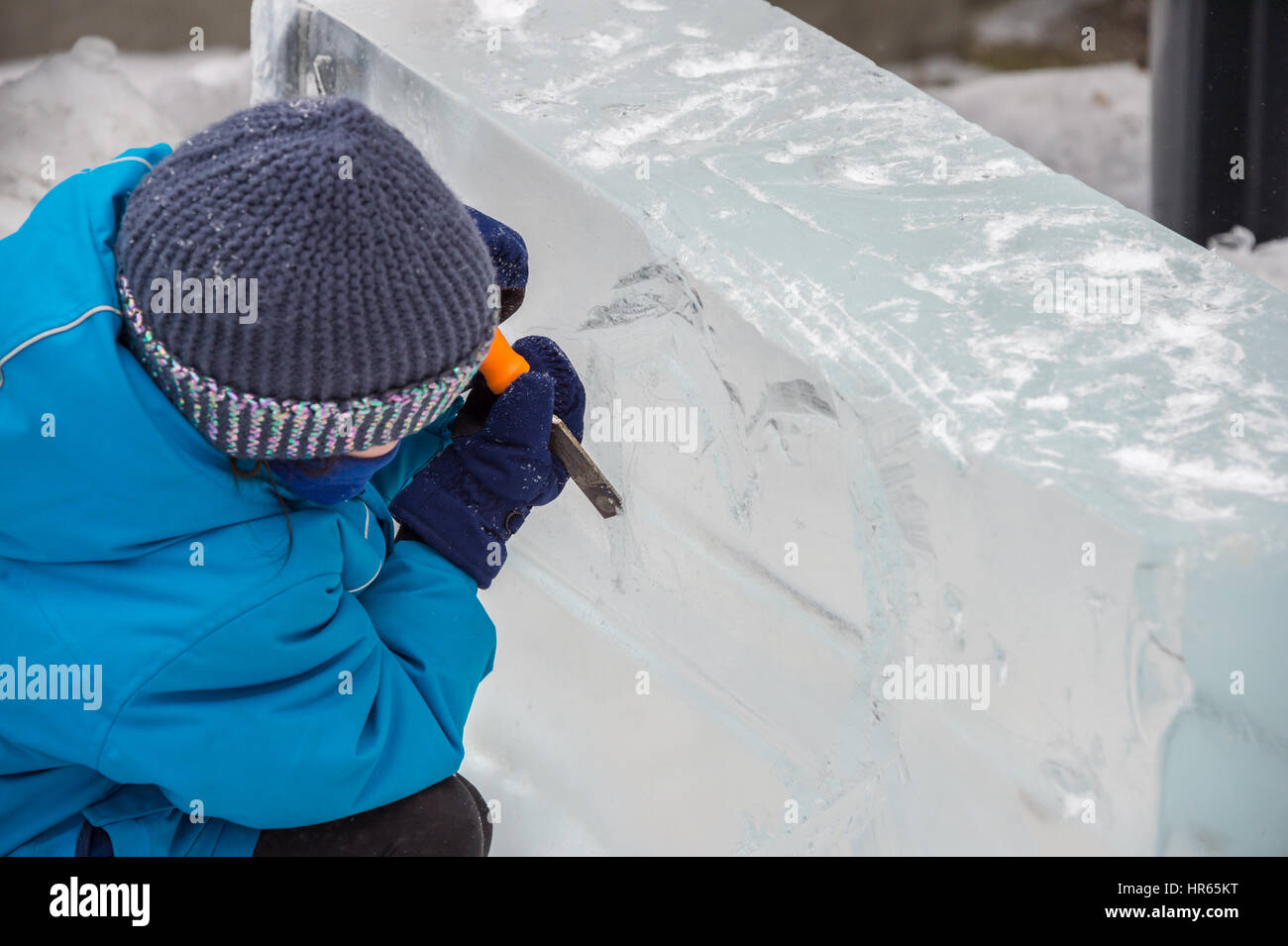 Montreal, CA - 4 February 2017: a child is carving a block of ice during Frima 'Fête des glaces' on Saint-Denis street. Stock Photo